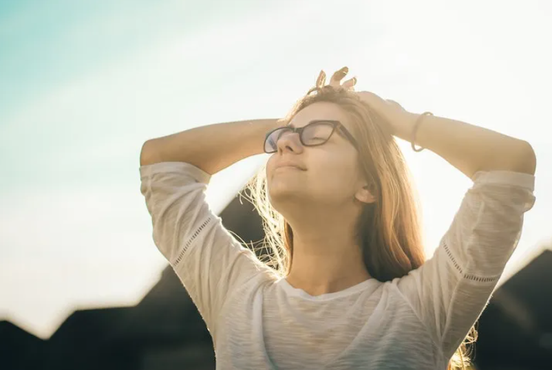 Mujer alcanzando la cima de una montaña, simbolizando el desarrollo personal y el liderazgo inspirador a través de hábitos clave como objetivos SMART y gestión del tiempo.